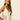 Woman wearing a beige one-piece swimsuit with lace details on a plain background