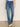 A person wears Sanctuary Clothing's sculpted hayden bootcut lucky streak jeans, featuring high-waisted blue denim with front patch pockets and white stitching, standing against a plain light backdrop, hands relaxed at their sides.