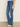 A person stands indoors in Sanctuary Clothing's sculpted hayden bootcut lucky streak jeans and beige pointed-toe shoes; only their upper body is partially visible against a neutral wall background.