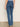 A person, shown from the waist down against a plain background, wears Sanctuary Clothing's Sculpted Hayden Bootcut Lucky Streak high-waisted blue jeans with flap back pockets and beige heeled shoes.