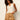 A woman with curly hair in sunglasses wears a sleeveless cream henley top and Sanctuary Clothing’s timeless satin lace short in toasted coconut, standing against a plain background.