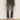 A person wearing Sanctuary Clothing astra kick crop jean in washed black denim, paired with a black top and black slip-on shoes, stands against a plain light-colored wall. The image is cropped to show only the lower half of the body.