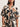 A woman wears the Sanctuary Clothing good time tie shirt lotus in petite sizing, featuring short sleeves, a button-down front, and an abstract black, brown, and white print. The dress ties at the waist; she accessorizes with a chunky bracelet.