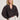 A woman with shoulder-length blonde hair wears the Sanctuary Clothing joyride relaxed volume blouse rhythmic, featuring a dark pattern, v-neck, and voluminous sleeves, styled with white high-waisted shorts and a brown belt against a light-colored wall.