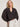 A woman with shoulder-length blonde hair wears the Sanctuary Clothing joyride relaxed volume blouse rhythmic, featuring a dark pattern, v-neck, and voluminous sleeves, styled with white high-waisted shorts and a brown belt against a light-colored wall.