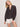 A woman with shoulder-length blonde hair wears the Sanctuary Clothing joyride relaxed volume blouse rhythmic, paired with white shorts, posing against a plain light background and looking at the camera in a relaxed stance.
