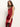 A woman with long brown hair models the Sanctuary Clothing revenge midi satin dress in crimson, featuring black lace near the hem. She stands against a plain white background, gazing just past the camera.