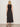 A woman with blonde hair wears the Sanctuary Clothing breakaway mix media midi dress in black, standing with her back to the camera against a plain light wall. She completes the look with flat, embellished sandals.