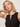 A woman with shoulder-length blonde hair confidently poses in the Sanctuary Clothing breakaway mix media midi dress in black, one arm raised and hand behind her head, against a plain background.