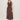 A woman with blonde hair and a relaxed expression wears the Sanctuary Clothing breakaway mix media midi dress in rich soil against a plain background, paired with black flat sandals. The dress is sleeveless, buttoned, and features a gathered skirt.
