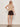 A woman models the Sanctuary Clothing "the perfect tee choco banana stripe," styled with dark brown shorts and sandals, posing against a plain light background with one hand on her hip and the other relaxed by her side.