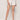 A woman models the Summit Short Chalk by Sanctuary Clothing—high-waisted, white denim shorts with front pockets and rolled cuffs—paired with a dark top and beige platform heels against a plain backdrop.