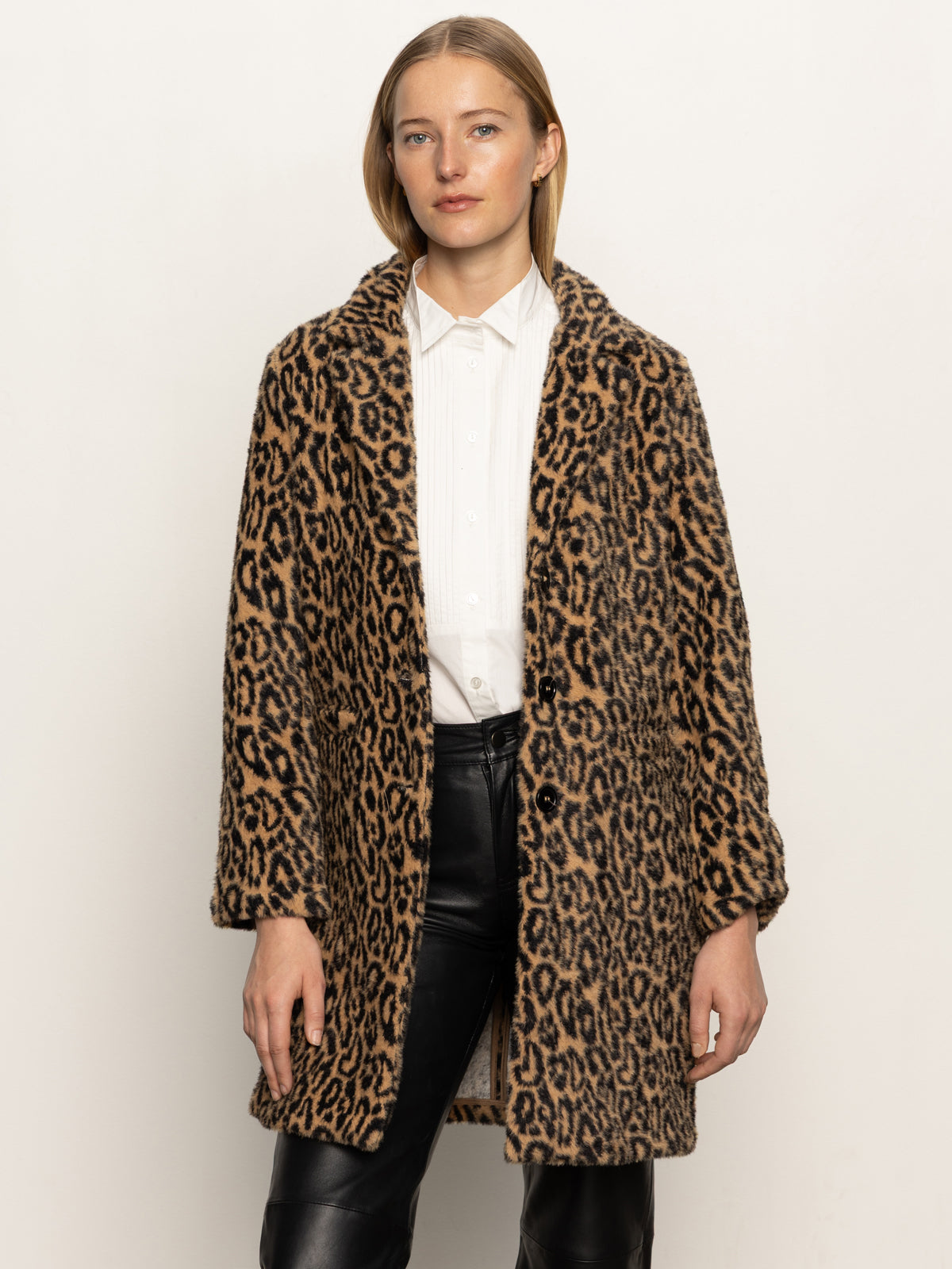 A person stands against a plain light background, wearing the Sanctuary Clothing "hometown jacket lynx" over a white button-up shirt and black leather pants, looking ahead with a neutral expression.