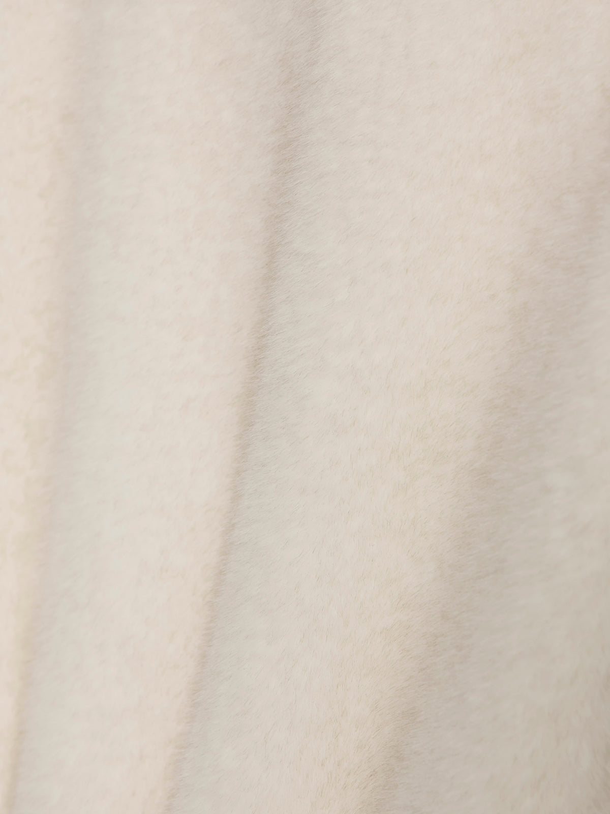 Close-up of the Sanctuary Clothing coco fur jacket in almond cream, featuring a soft, light beige textured fabric with subtle vertical folds and a cozy, slightly fuzzy surface.