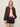 A woman with blonde hair models the Sanctuary Clothing linen bubble jacket in rich soil over a light pink top, dark denim shorts, and a beige belt, standing against a plain light-colored background with one hand in her pocket.