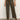 A person wearing Sanctuary Clothing™s marine crop trouser pant fatigue in olive green with front patch pockets, paired with a black top and brown suede heeled ankle boots, stands on a gray floor against a plain light background.