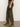 A person stands on a gray floor wearing Sanctuary Clothing's the marine crop trouser pant fatigue in olive-green with tan suede low-heel ankle boots, shown from the side against a plain light background.