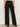 A person faces away wearing the Sanctuary Clothing runway ponte trouser in black�high-waisted, wide-leg pants with two back welt pockets, paired with black heeled shoes. The look is set against a plain, light-colored background.