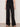 A person wears the Sanctuary Clothing casual track pant in black summer sand with a white side stripe, paired with a black sleeveless top and sandals, standing against a plain background.