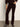 A person wearing Sanctuary Clothing's velveteen brook bootcut pant in dark crimson stands against a plain light background. The photo is cropped to show the body from shoulder to foot.
