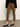 A person wears Sanctuary Clothing¢€š¬€ž¢s fairway legging dirty martini, a black long-sleeve top, and black flats while standing on a concrete floor against a light wall. The photo is cropped at the torso and ankles.