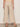A person stands facing away, wearing Sanctuary Clothing's lily stripe cropped pant in lido stripe petite sizing and beige moccasin-style shoes, with a gray floor and a plain light-colored wall in the background.