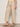 A person wears Sanctuary Clothing's lily stripe cropped pant in lido stripe (petite), paired with a yellow top and tan sandals, standing against a light-colored wall.