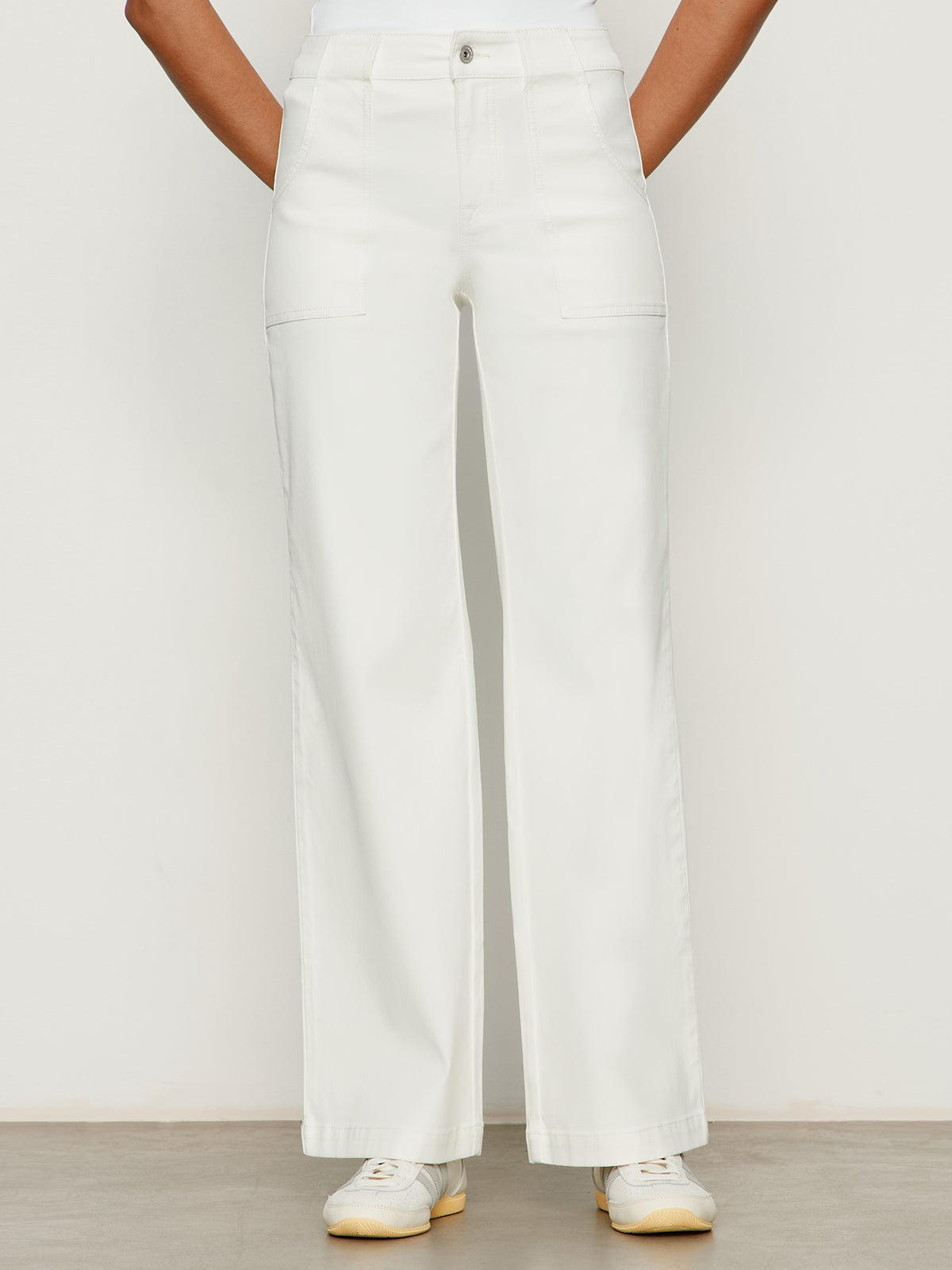 A person wears the Sanctuary Clothing sculpted insider wide leg pant in chalk, featuring front patch pockets and a high waist, paired with white sneakers, standing against a plain light background.