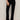 A person models the velveteen brook bootcut pant in black petites by Sanctuary Clothing, standing against a neutral background with one hand in a pocket; their head and upper body are out of frame.