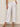 Wearing Sanctuary Clothing's "angels cargo pant white" with pockets and button details, styled with light brown heeled sandals and a pale yellow knit top. The image is cropped to show only the lower torso and legs.