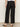 A person is shown from the back, standing against a plain background, wearing the scout linen barrel pant in black by Sanctuary Clothing, paired with a tucked-in white top and black low-heeled slip-on shoes.