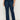 A person wears Sanctuary Clothing’s "Hayden Bootcut Jean Plot Twist" (extended sizing), featuring high-waisted dark blue denim and front patch pockets, styled with black ankle boots against a plain light background.
