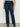 A person wears Sanctuary Clothing’s "Hayden Bootcut Jean Plot Twist" (extended sizing), featuring high-waisted dark blue denim and front patch pockets, styled with black ankle boots against a plain light background.