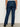 A person wearing Sanctuary Clothing's hayden bootcut jean plot twist extended sizing, shown from the back, with large back pockets and black heeled shoes, standing against a plain light-colored wall.