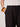 Someone wearing Sanctuary Clothing's shoreline linen pants in black and a white ribbed sleeveless top has one hand in their pocket, accessorized with two chunky bracelets in amber and brown tones.