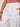 A person wearing Sanctuary Clothing's melody micro linen balloon white pants with hands in pockets. They pair it with a rust top and chunky brown bracelet. The image is cropped to show only the lower torso and upper legs.