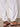 A person wears Sanctuary Clothing's melody micro linen balloon white pants, paired with black studded sandals, standing on a smooth light-colored floor. Only their lower legs and feet are visible.