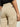A person is shown from behind, waist down, wearing high-waisted foundry pant khaki by Sanctuary Clothing with large back pockets and a visible brand label, against a light background.