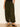 A person wears Sanctuary Clothing's the moment volume pant in midnight moss, featuring a loose fit and elastic cuffs, paired with a black top and black sandals, standing against a light wall on a wooden floor.