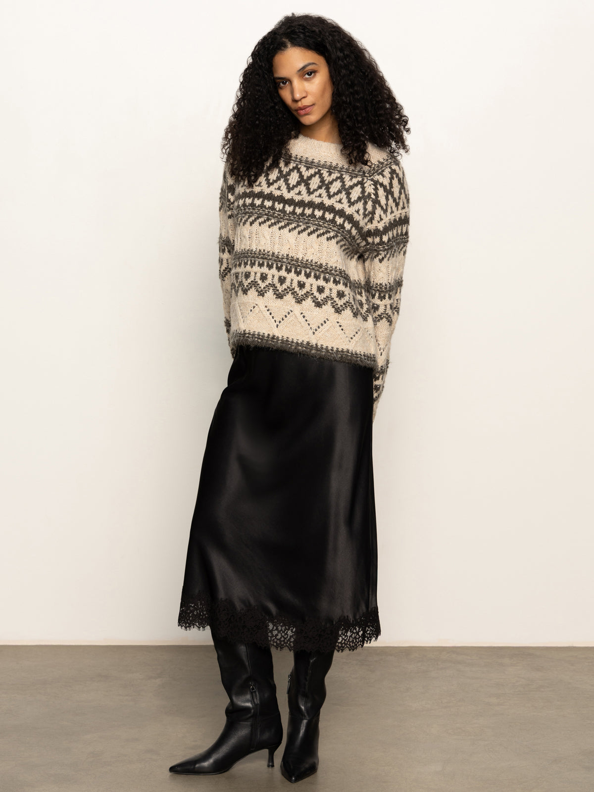 Woman wearing a patterned sweater and black skirt against a plain background