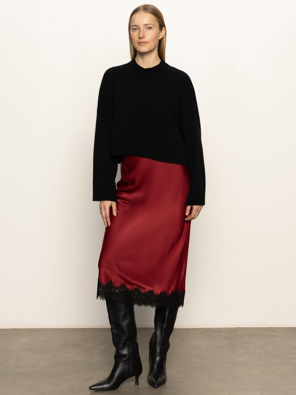 Person wearing a black top and red skirt with black boots against a white background