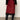 Red skirt with black lace trim worn with black knee-high boots on a neutral background