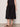 Someone wearing the Sanctuary Clothing "Matter of Time" poplin skirt in black, paired with a black sleeveless top and sandals, stands on a neutral floor against a light background.
