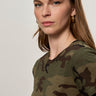 A woman with long brown hair and gold hoop earrings models Sanctuary Clothing's the perfect tee hiker camo, confidently facing the camera against a plain background.