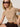 A woman with blonde hair and dark sunglasses sits on a chair wearing Sanctuary Clothing's the perfect tee choco banana stripe and brown shorts, with a neutral expression and one hand resting on her hip.