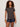 Woman with curly hair wears Sanctuary Clothing’s the perfect tee rhythmic—a short-sleeve patterned top—paired with dark denim shorts and brown bangles, standing against a plain light background.
