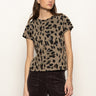 A woman with long brown hair wears the Sanctuary Clothing double knit perfect tee in winter leopard and dark pants, standing against an off-white background. She looks to the side with a neutral expression.