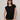 Woman wearing a black sleeveless top and green pants against a plain background