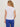 Woman wearing a white t-shirt and blue pants against a beige background
