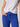 Person wearing a white top and blue pants with a neutral background